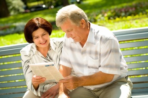 Happy successful attractive elderly couple reading together outd